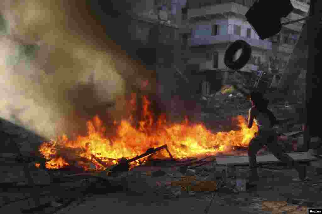 A Free Syrian Army fighter watches after setting tires and other objects on fire to provide cover from snipers loyal to Syria's President Bashar al-Assad, in Aleppo's Salaheddine district, Sept. 25, 2013.