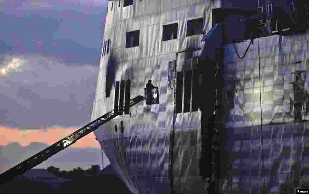 Petugas pemadam kebakaran berdiri di tangga untuk memeriksa dek mobil dan truk kapal feri&nbsp; Norman Atlantic yang berlabuh di pelabuhan Brindisi, 2 Januari 2015. &nbsp;