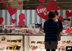 A woman buys Valentine's Day chocolates at a store in Tokyo Tuesday, Feb. 14, 2012. (AP Photo/Shizuo Kambayashi)