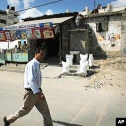 A man walks past several bags of food aid sitting in front of a store in the Shati refugee camp in Gaza City.