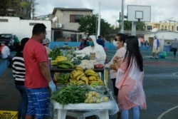 In this May 2, 2020 photo, local farmers, wearing protective as a measure to curb the spread of the new coronavirus, sell their products to residents, in San Cristobal, Galapagos Islands, Ecuador. (AP Photo/Adrian Vasquez)