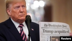 Le président américain Donald Trump brandit une copie de la Une du Washington Post qui annonce qu'il a été acquitté par le Sénat, le 6 février 2020.