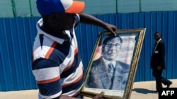 Mmoja wa waombolezaji abeba picha ya marehemu Robert Mugabe, 11 septemba 2019.