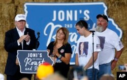 Republican presidential candidate Donald Trump shares the stage with the family of Sarah Root at a campaign event at the Iowa State Fairgrounds in Des Moines, Aug. 27, 2016. Root was killed this year after her car was hit by another. The driver, who was d