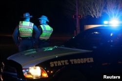 Texas state troopers keep watch at a checkpoint as nearby law enforcement personnel investigate an incident that they said involved an incendiary device in the 9800 block of Brodie Lane in Austin, Texas, March 20, 2018.
