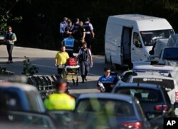 An ambulance stretcher is pushed on the road where Police bomb squad members work by a road near Subirats, Spain, Aug. 21, 2017.