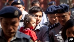 Reuters journalist Kyaw Soe Oo carrying his daughter is escorted by Myanmar police as he re-enter to the trial after a break Feb. 1, 2018, outside of Yangon, Myanmar.