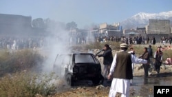 Pakistani firefighters extinguish a fire in a vechile at the site of a bomb explosion at a market in Parachinar, the capital of Kurram tribal district, Dec. 13, 2015.