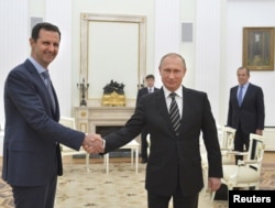 Russian President Vladimir Putin (R) shakes hands with Syrian President Bashar al-Assad during a meeting at the Kremlin in Moscow, Russia, October 20, 2015.