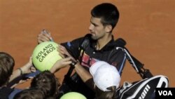 Novak Djokovic memberikan tanda tangan kepada penggemarnya setelah petenis Romania Victor Hanescu mengundurkan diri dari putaran kedua Perancis Terbuka hari Rabu (25/5).