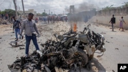 Pripadnici snaga bezbednosti i civili u blizini olupine nakon napada automobilom-bombom na gradskok policijskog komesara u Mogadišu, Somalija, 10. jula 2021.
