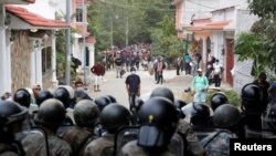 FILE - Guatemalan soldiers block a street as Honduran migrants gather after Guatemalan security forces cleared a road where they were camping after authorities halted their trek to the United States, in Vado Hondo, Guatemala, Jan. 18, 2021. 