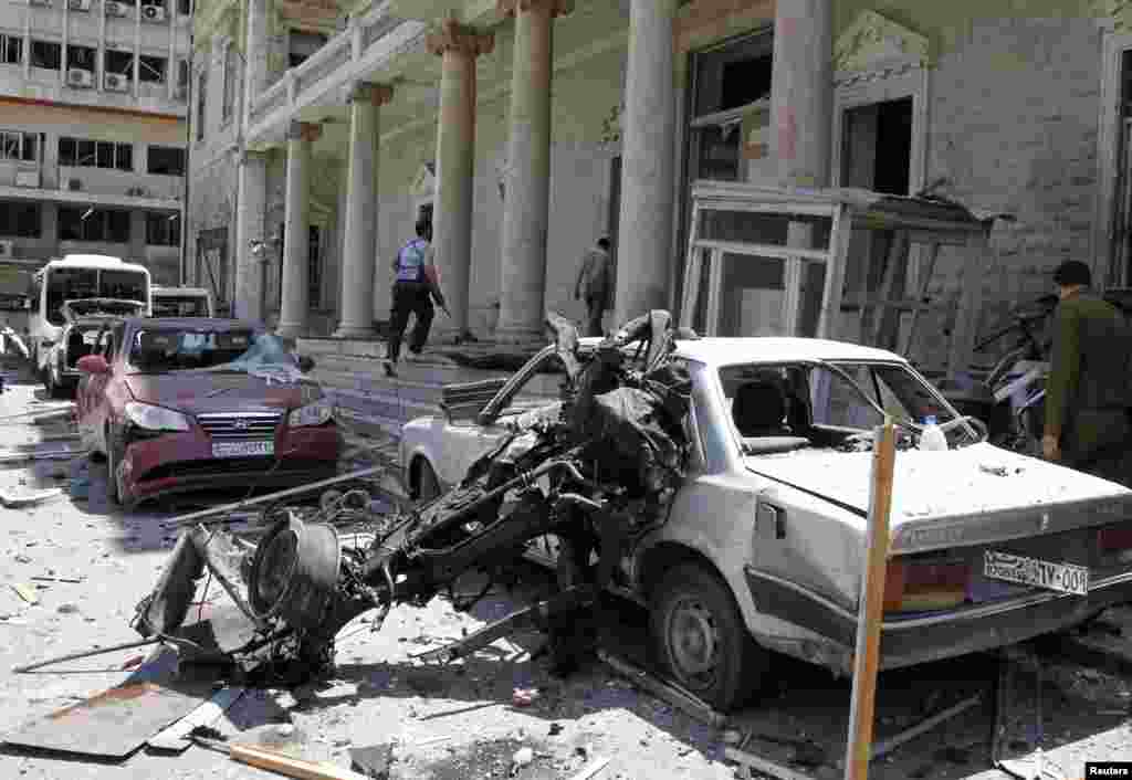 Security personnel walk in front of the former Interior Ministry building after a blast at Marjeh Square in Damascus, April 30, 2013. 