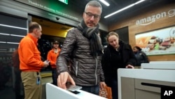 A customer scans his Amazon Go cellphone app at the entrance as he heads into an Amazon Go store, Monday, Jan. 22, 2018, in Seattle. (AP Photo/Elaine Thompson)