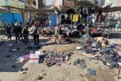 FILE - People and security forces gather at the site of a deadly bomb attack in a market selling used clothes, in Baghdad, Jan. 21, 2021.