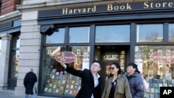 Students pose for a selfie outside the Harvard Book Store, March 9, 2017, in Cambridge, Mass. Readers have been flocking to classic works of dystopian fiction. Some have shot to the top of best-seller lists, including George Orwell's "1984" and Margaret A