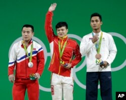 브라질 리우올림픽에 출전한 북한 역도 국가대표팀 엄윤철 선수(왼쪽)가 남자 56kg급에서 은메달을 목에 걸었다. 금메달은 중국 룽칭취안(가운데) 선수에게 돌아갔다.