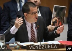 Venezuela Foreign Affairs Minister Jorge Arreaza shows picture he said represent opposition members initiating violence, during a meeting on Venezuela in the Security Council at U.N. headquarters, Feb. 26, 2019.