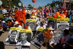Cambodian land activists display photos of their detained colleagues during a gathering to mark Human Rights Day, in front of National Assembly, in Phnom Penh, Cambodia, Wednesday, Dec. 10, 2014. (AP Photo/Heng Sinith)