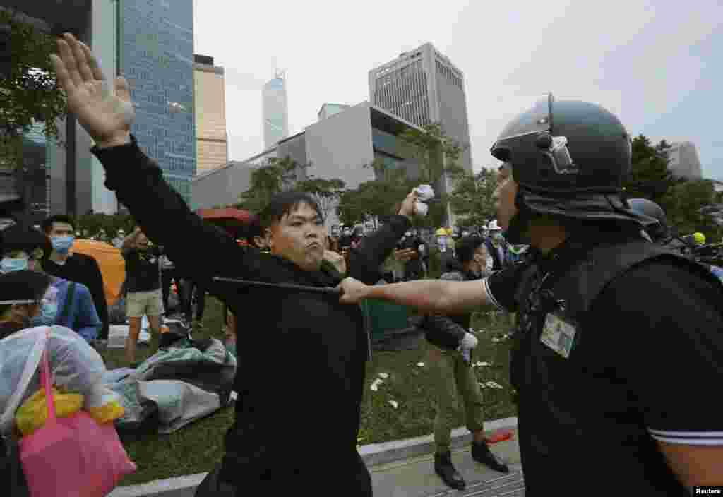 A pro-democracy protester blocks a riot policeman during a clash outside the government headquarters in Hong Kong, December 1, 2014.