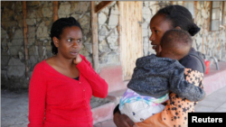 Pendiri sekolah menengah Serene Haven, Elizabeth Wanjiru berbicara dengan Josephine Wanjiru, 19, yang menggendong anaknya di luar asrama di sekolah menengah Serene Haven. (Foto: REUTERS/Monicah Mwangi)
