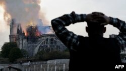 Warga yang berada di dekat lokasi kebakaran Katedral Notre Dame bersedih atas musibah yang menimpa salah satu ikon kota Paris ini, Senin (15/4). 