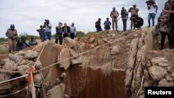 FILE - People watch as Senzo Mchunu, South African police minister (not pictured), inspects outside the mineshaft where it is estimated that illegal miners are believed to be hiding underground, in Stilfontein, Nov. 15, 2024.