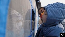 Seorang petugas medis yang mengenakan baju pelindung mengambil sampel dari seorang anak kecil dalam program tes COVID-19 massal di Tianjin, pada 9 Januari 2022. (Foto: Xinhua via AP/Zhao Zishuo)