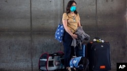 Seorang pelancong dan hewan peliharaannya menunggu untuk mendaftar penerbangan pulang di bandara internasional La Aurora di Guatemala City, 27 Maret 2020. (Foto: AP)