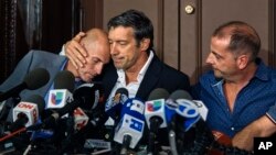 Survivors of the attack Guillermo Banchini, center, hugs Ivan Brajkovic, left, next to Juan Pablo Trevisan, during a press conference, Nov. 3, 2017, in New York.