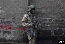 A member of the M23 rebel group picks an unexploded mortar shell from the floor during a cleanup exercise in Goma, Democratic Republic of Congo, on Feb. 1, 2025.