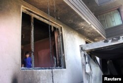 FILE - An Afghan boy is seen inside a burnt building after a Taliban attack in Ghazni city, Afghanistan, Aug. 15, 2018.