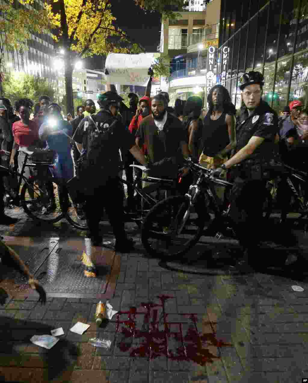 Police circle an area where a pool of blood lies after a man was injured during a protest of Tuesday's fatal police shooting of Keith Lamont Scott in Charlotte, N.C., Sept. 21, 2016. 