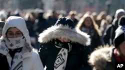 Para pejalan kaki berusaha menghangat diri saat berjalan di Times Square, New York, 27 Desember 2017. 