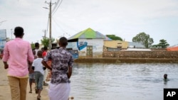 A child swims in the floodwaters as others walk past in the town of Beledweyne, in central Somalia, Nov. 4, 2019. Authorities have not yet said how many people died in Somalia's recent flooding, the country's worst in recent history.