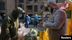 មនុស្ស​កំពុង​ប្រមូល​បន្លែ​ដែល​ទិញ​តាម​រយៈ​ការ​បញ្ជាទិញ​ជា​ក្រុម​នៅ​ឯ​ច្រក​ចូល​ទៅ​កន្លែង​រស់​នៅ​ក្នុង​ទីក្រុង​វូហាន ប្រទេស​ចិន ដែល​ជា​កន្លែង​ផ្ទុះ​ឡើង​នៃ​មេរោគ​កូរ៉ូណាវីរុស នៅ​ខេត្តHubei ប្រទេស​ចិន កាល​ពី​ថ្ងៃ​ទី​២១ កុម្ភៈ ២០២០។