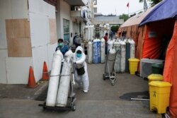 Seorang petugas kesehatan mendorong tabung oksigen di dekat tenda-tenda darurat akibat penuhnya kamar sebuah rumah sakit di Bekasi (foto: dok).