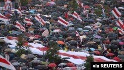 People take cover from rain under umbrellas during an opposition rally to protest against police brutality and to reject the presidential election results in Minsk, Belarus, Sept.r 6, 2020. 