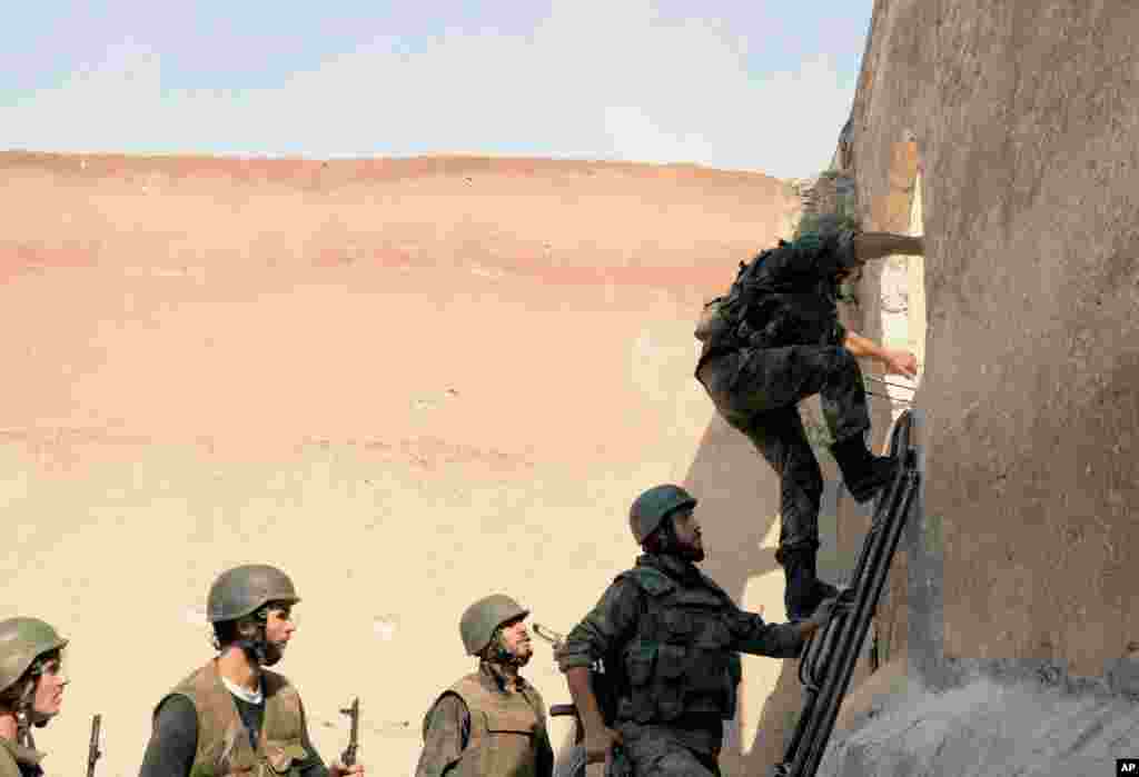 In this photo released by the Syrian official news agency SANA, Syrian government forces storm a building in the al-Arqoub district of Aleppo, Syria, Sept. 24, 2012. 