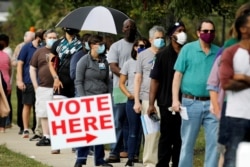 FILE - Voters wait in line to enter a polling place and cast their ballots on the first day of the state's in-person early voting for the general elections in Durham, North Carolina, Oct. 15, 2020.