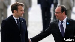 Presiden Perancis Francois Hollande (kanan) yang akan segera mengakhiri masa tugasnya, menggamit lengan President terpilih Emmanuel Macron, saat menghadiri upacara untuk menandai diakhirinya Perang Dunia II di Tomb of the Unknown Soldier (Tugu Peringatan untuk Tentara-tentara yang tidak dikenal) di the Arc de Triomphe, Paris, 8 Mei 2017. (Foto: REUTERS/Francois Mori)