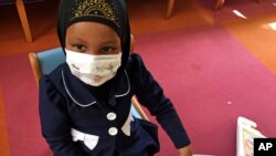 Amira Hassan, of Burnsville, Minnesota, plays in the waiting room at the specialty clinic at Children's Minnesota in Minneapolis, Minnesota, May 2, 2017. Amira went to the hospital's clinic for a routine wellness check, but had to wear a mask to protect her from measles after an outbreak.
