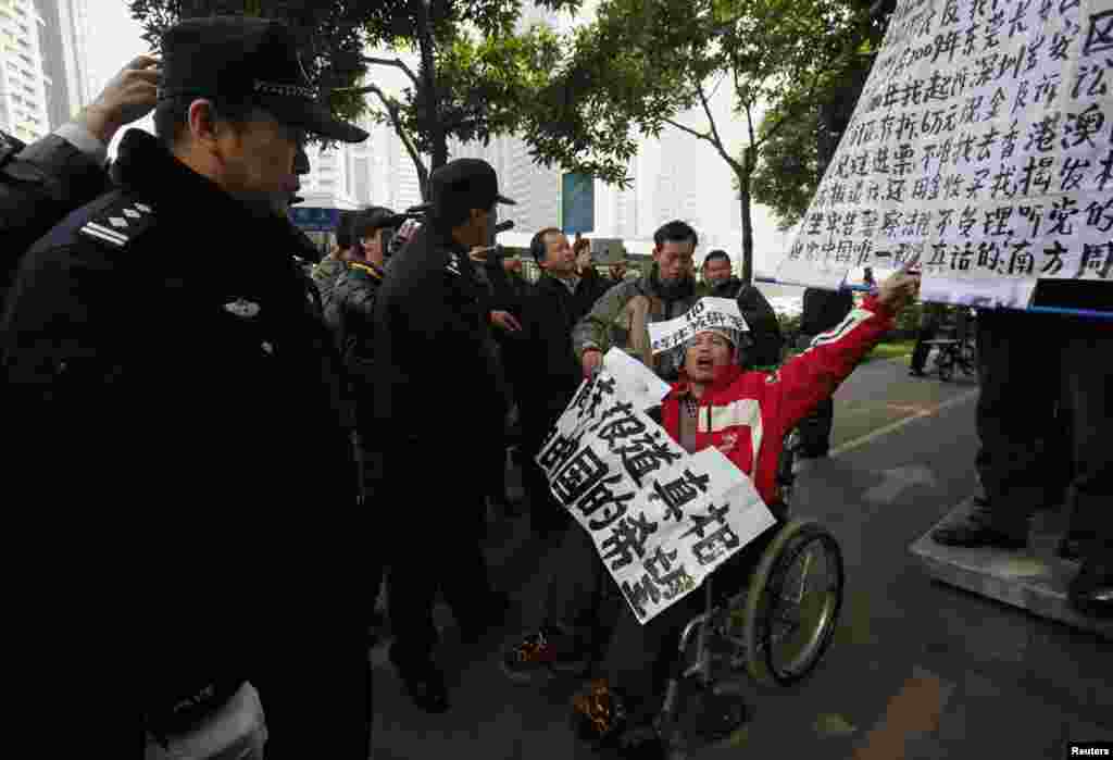 2013年1月10日，一位坐轮椅的《南方周末》支持者在广州《南周》总部附近在警察面前呼喊口号。他随后被便衣警察带走。