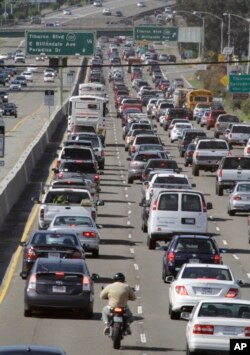 FILE - A motorcyclist rides between lanes as traffic backs up on U.S. Highway 101 in Mill Valley, Calif., May 26, 2011. California, 16 other states and the District of Columbia sued the Trump administration on May 1, 2018, over its plans to scrap standards on vehicle greenhouse gas emissions, which help set gas mileage rules.