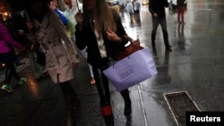 FILE - Consumers navigate high-end retail stores along 5th Avenue, New York City.