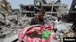 Palestinians inspect the site of an Israeli strike on a house, in Nuseirat