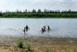 In this handout photo taken Sunday, June 21, 2020 and provided by Olga Burtseva, children play in the Krugloe lake outside Verkhoyansk, the Sakha Republic, about 4660 kilometers northeast of Moscow, Russia. (Olga Burtseva via AP)