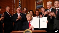 U.S. President Donald Trump holds up a signed Antiquities Executive Order during a ceremony at the Interior Department in Washington, April, 26, 2017. 