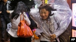 A woman braves strong wind in Hong Kong Monday, Sept. 15, 2014.