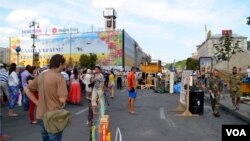 Tourists look on as protesters start pulling down their remaining Maidan tents, Independence Square, Kyiv, Ukraine, Aug. 11, 2014. (Jamie Dettmer/VOA)